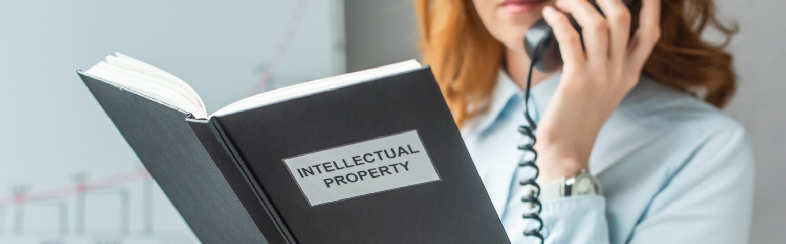 Cropped view of book with intellectual property lettering with blurred businesswoman on background,